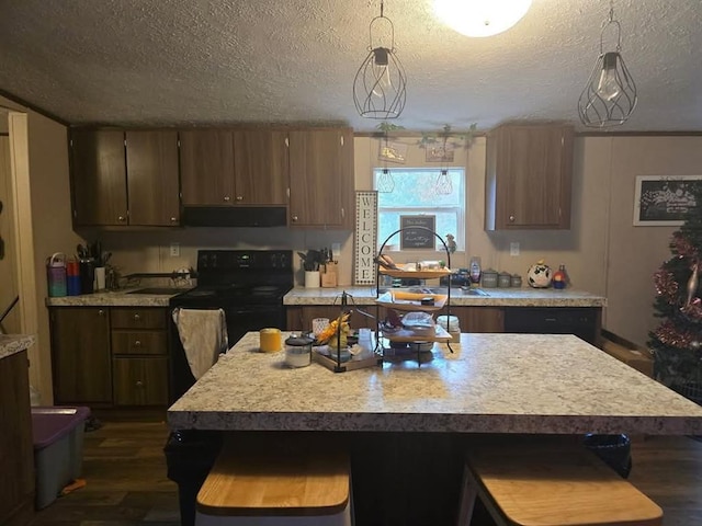 332841 E 890th Rd, Wellston, OK 74881 - kitchen featuring ventilation hood, light countertops, dark wood-style floors, a kitchen breakfast bar, and a textured ceiling