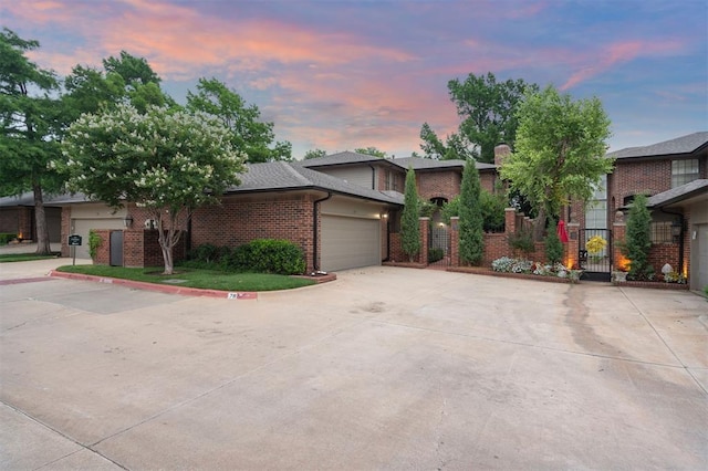 6206 Waterford Blvd Unit 78, Oklahoma City, OK 73118 - view of front of property featuring brick siding, an attached garage, a gate, concrete driveway, and a chimney