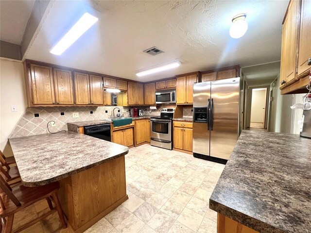 416 E Quail Rd, Chickasha, OK 73018 - kitchen with stainless steel appliances, a peninsula, decorative backsplash, and a sink