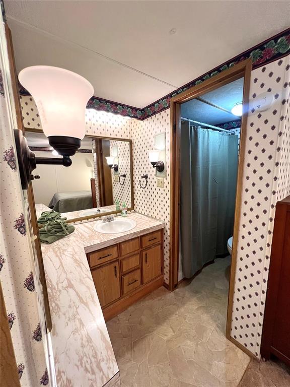 416 E Quail Rd, Chickasha, OK 73018 - bathroom featuring vanity, toilet, and stone finish floors