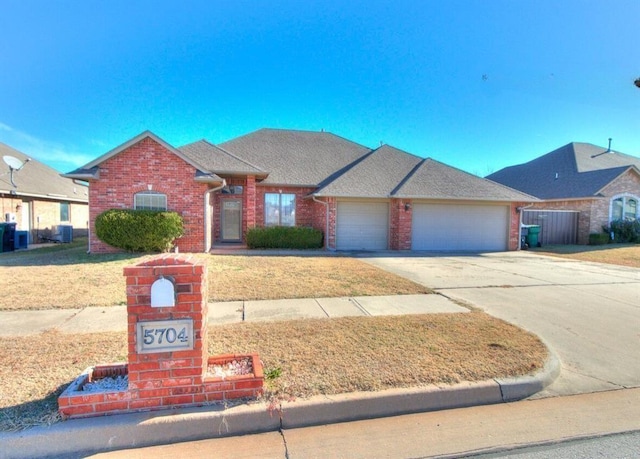 5704 Bent Creek Dr, Oklahoma City, OK 73135 - view of front of property with an attached garage, brick siding, concrete driveway, a front yard, and central AC unit