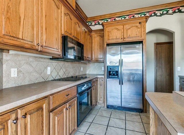 5704 Bent Creek Dr, Oklahoma City, OK 73135 - kitchen featuring black appliances, arched walkways, tasteful backsplash, brown cabinetry, and light countertops