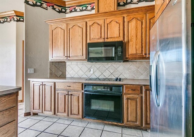 5704 Bent Creek Dr, Oklahoma City, OK 73135 - kitchen featuring black appliances, backsplash, light tile patterned floors, light countertops, and a textured wall