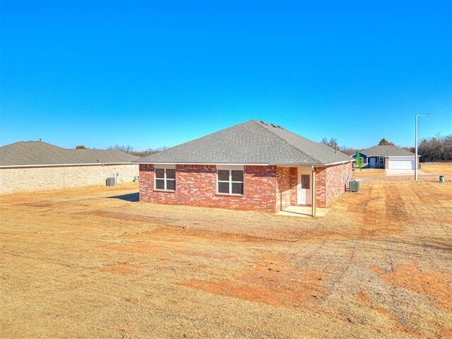 813 Stella Trl, Guthrie, OK 73044 - back of house featuring cooling unit, a lawn, and brick siding
