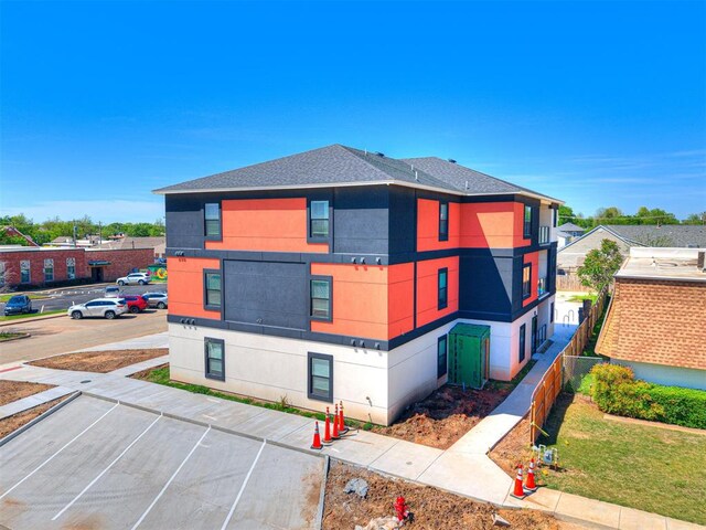 103 E Edwards St, Edmond, OK 73034 - view of home's exterior featuring stucco siding, uncovered parking, and roof with shingles