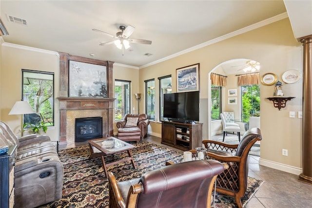 3201 Pinehurst Dr, Norman, OK 73072 - tiled living room featuring a ceiling fan, ornamental molding, a fireplace, and arched walkways