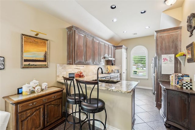 3201 Pinehurst Dr, Norman, OK 73072 - kitchen with decorative backsplash, a peninsula, tile patterned floors, under cabinet range hood, and a breakfast bar area