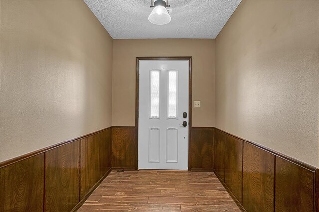 404 Comanche Trl, Altus, OK 73521 - doorway with wood walls, a wainscoted wall, wood finished floors, and a textured ceiling