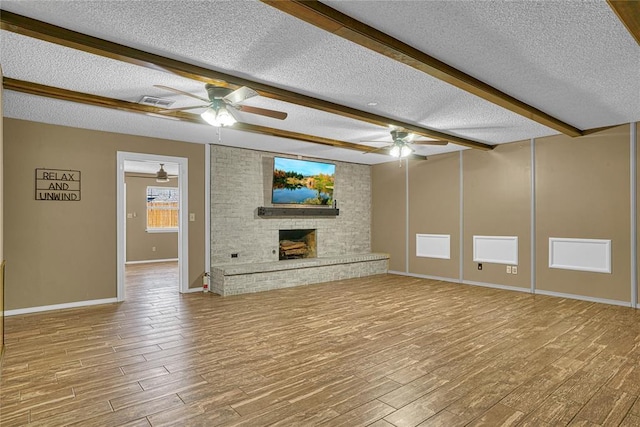 404 Comanche Trl, Altus, OK 73521 - unfurnished living room with a ceiling fan, a textured ceiling, wood finished floors, baseboards, and a brick fireplace