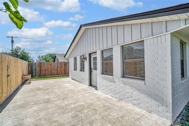404 Comanche Trl, Altus, OK 73521 - view of side of property with board and batten siding, a patio, a fenced backyard, and brick siding