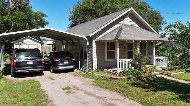 305 N Reimer St, Corn, OK 73024 - view of front facade with covered porch, roof with shingles, a detached carport, and driveway