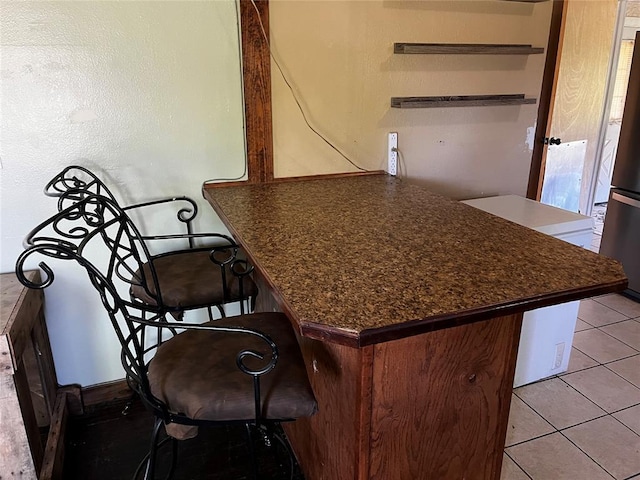 305 N Reimer St, Corn, OK 73024 - kitchen featuring dark countertops, open shelves, freestanding refrigerator, a peninsula, and a breakfast bar area
