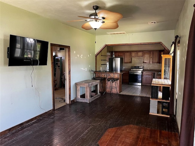 305 N Reimer St, Corn, OK 73024 - kitchen with appliances with stainless steel finishes, wood-type flooring, ceiling fan, tasteful backsplash, and dark countertops