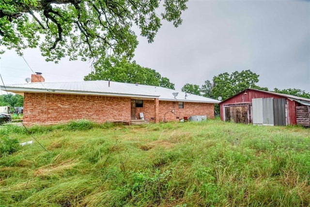 back of property with a chimney, brick siding, and an outbuilding