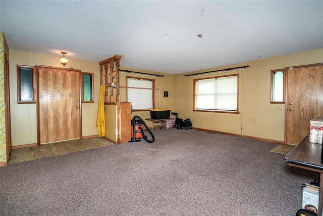 unfurnished living room with baseboards, a textured ceiling, and carpet flooring
