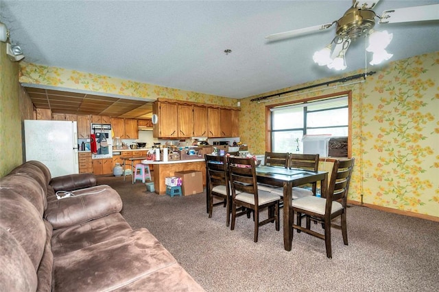 dining area with wallpapered walls, a ceiling fan, light carpet, and a textured ceiling