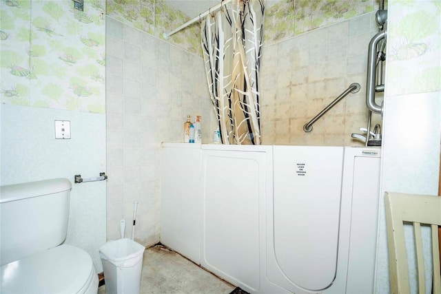 full bathroom with toilet, tile walls, and a shower with curtain