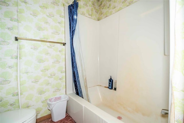 bathroom featuring wallpapered walls, shower / bathtub combination with curtain, and toilet