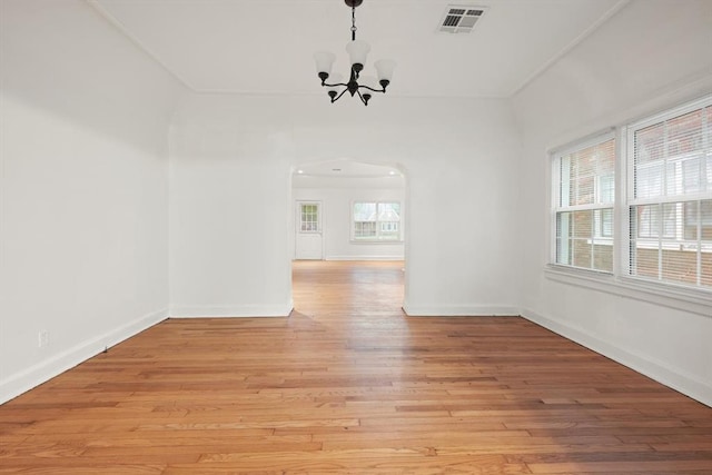905 NE 21st St, Oklahoma City, OK 73105 - unfurnished dining area featuring arched walkways, a chandelier, light wood-style floors, and baseboards