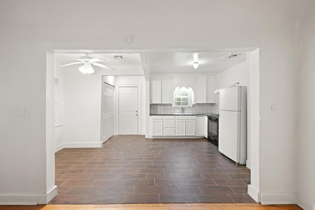 905 NE 21st St, Oklahoma City, OK 73105 - kitchen with freestanding refrigerator, black range, decorative backsplash, white cabinets, and ceiling fan