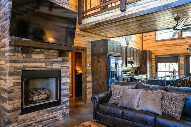 161 Champion Way, Broken Bow, OK 74728 - living room featuring wood walls, a towering ceiling, and a stone fireplace