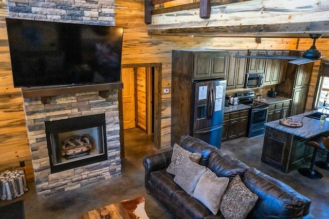 161 Champion Way, Broken Bow, OK 74728 - kitchen featuring stainless steel appliances, wood walls, a sink, concrete flooring, and a stone fireplace