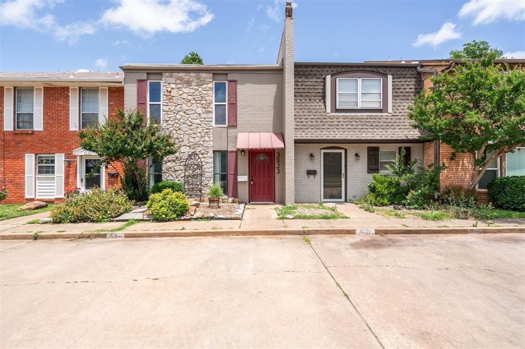 3023 W Wilshire Blvd, Oklahoma City, OK 73116 - view of property featuring brick siding, mansard roof, and roof with shingles
