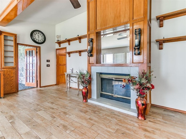 17612 Durbin Park Rd, Edmond, OK 73012 - living room featuring ceiling fan, a fireplace, light wood finished floors, baseboards, and a towering ceiling
