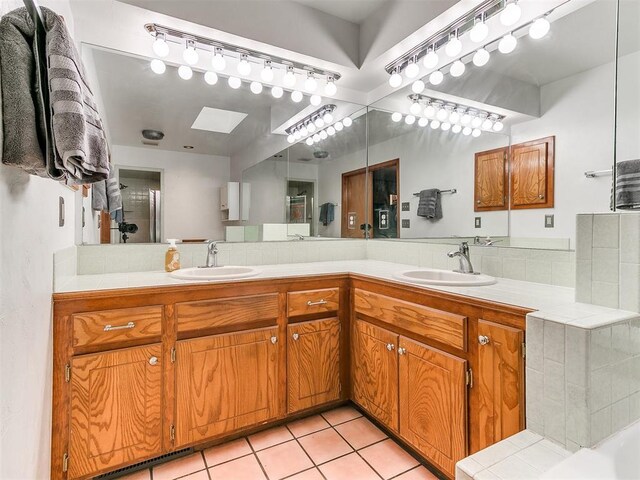 17612 Durbin Park Rd, Edmond, OK 73012 - full bath featuring a skylight, double vanity, tasteful backsplash, tile patterned floors, and a tub to relax in