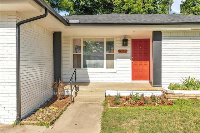 5712 N Roff Ave, Oklahoma City, OK 73112 - view of exterior entry featuring brick siding, covered porch, and roof with shingles