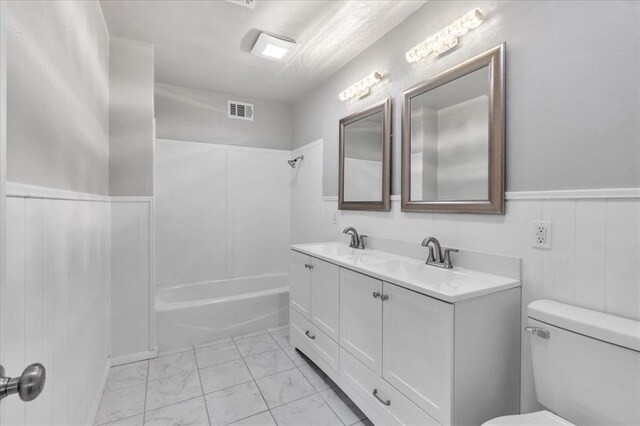 5712 N Roff Ave, Oklahoma City, OK 73112 - full bath with marble look tile flooring, double vanity, toilet, a wainscoted wall, and shower / bath combination