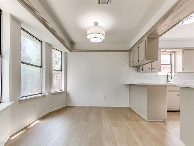 1033 Linn Ln, Yukon, OK 73099 - kitchen featuring light wood-style floors, light countertops, tasteful backsplash, a peninsula, and baseboards