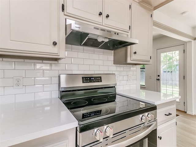 1033 Linn Ln, Yukon, OK 73099 - kitchen featuring under cabinet range hood, stainless steel range with electric stovetop, light countertops, backsplash, and white cabinetry