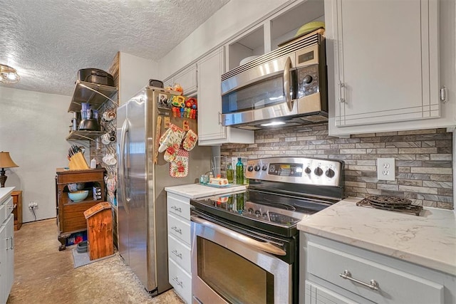 1301 Canterbury Blvd, Altus, OK 73521 - kitchen featuring appliances with stainless steel finishes, a textured ceiling, backsplash, and light stone countertops
