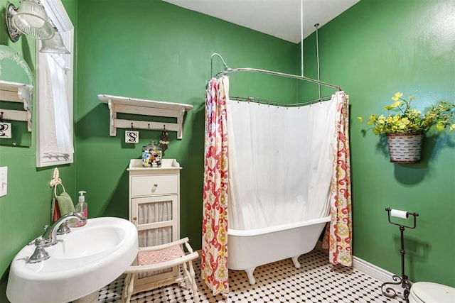 516 S Macomb Ave, El Reno, OK 73036 - full bathroom featuring a freestanding tub, toilet, a sink, a shower with curtain, and baseboards