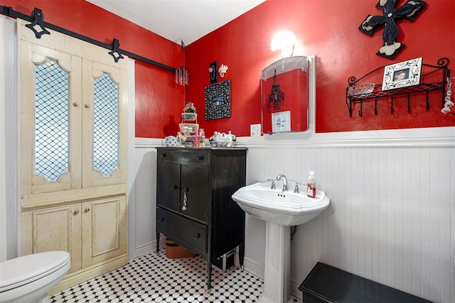 516 S Macomb Ave, El Reno, OK 73036 - bathroom featuring a wainscoted wall, tile patterned floors, toilet, and a sink