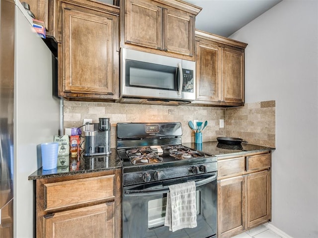 5805 Marblewood Dr, Oklahoma City, OK 73179 - kitchen featuring stainless steel microwave, black range with gas stovetop, freestanding refrigerator, tasteful backsplash, and dark stone countertops