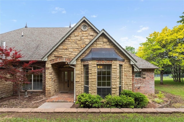 6373 Stone Valley Dr, Edmond, OK 73034 - tudor home featuring a shingled roof and stone siding