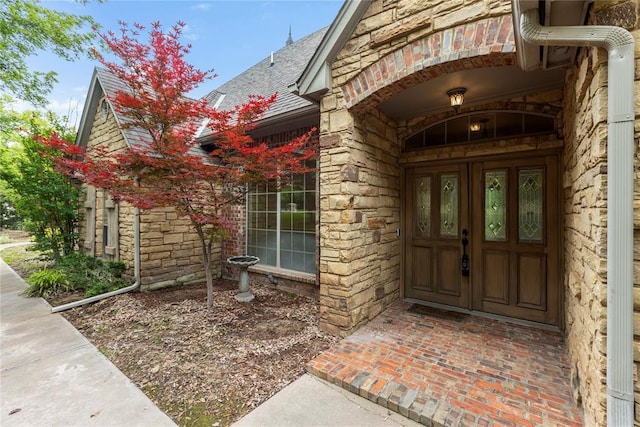 6373 Stone Valley Dr, Edmond, OK 73034 - doorway to property with a shingled roof, stone siding, and brick siding