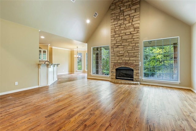 6373 Stone Valley Dr, Edmond, OK 73034 - unfurnished living room with high vaulted ceiling, plenty of natural light, light wood finished floors, a stone fireplace, and baseboards
