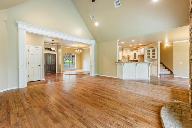 6373 Stone Valley Dr, Edmond, OK 73034 - unfurnished living room with high vaulted ceiling, a chandelier, hardwood / wood-style flooring, stairway, and baseboards