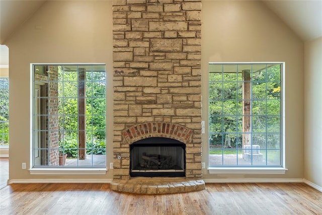 6373 Stone Valley Dr, Edmond, OK 73034 - unfurnished living room featuring wood finished floors, a stone fireplace, healthy amount of natural light, baseboards, and high vaulted ceiling