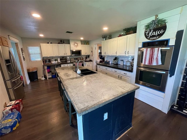 513 E Monroe St, Maud, OK 74854 - kitchen featuring a sink, stainless steel appliances, dark wood-type flooring, white cabinets, and recessed lighting