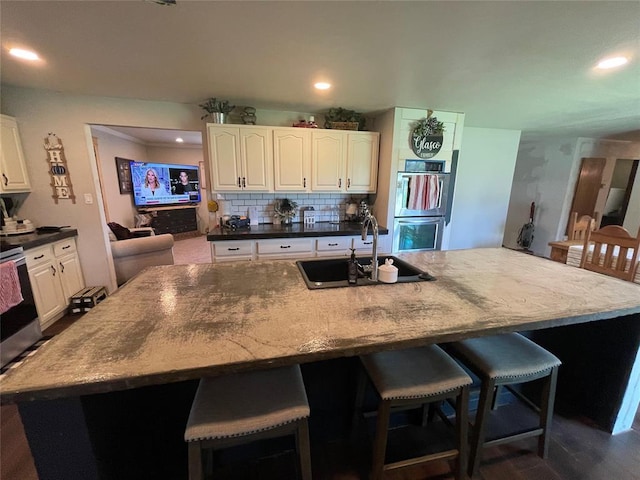 513 E Monroe St, Maud, OK 74854 - kitchen featuring double oven, a sink, a large island with sink, white cabinets, and recessed lighting