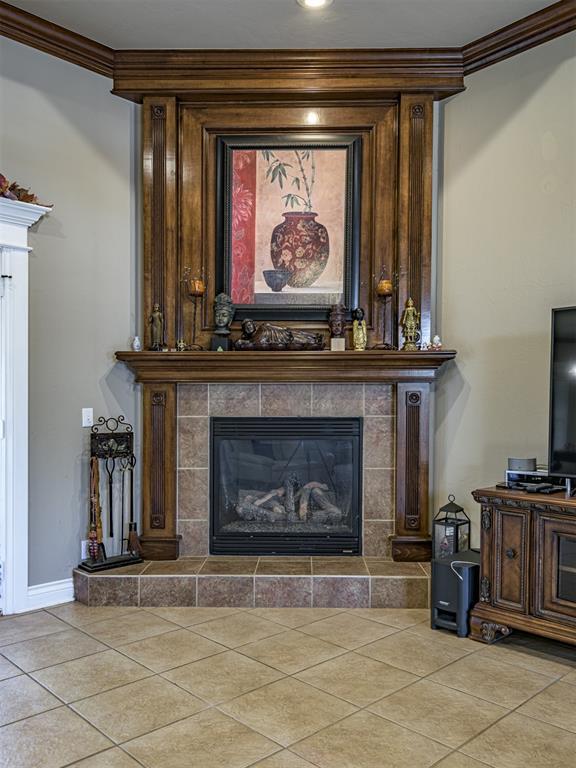 421 Meadow Run Ct, Yukon, OK 73099 - detailed view of a tile fireplace, ornamental molding, and baseboards