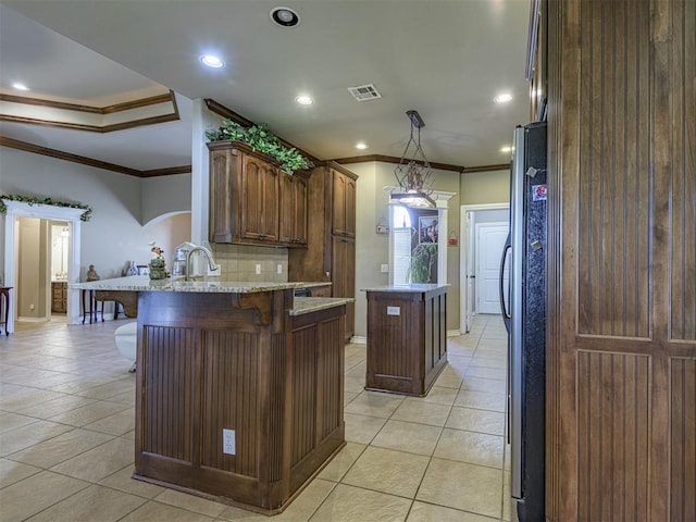 421 Meadow Run Ct, Yukon, OK 73099 - kitchen with crown molding, a kitchen island, light tile patterned floors, a peninsula, and a kitchen breakfast bar