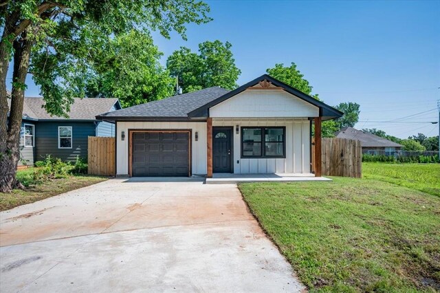 1435 NE 27th St, Oklahoma City, OK 73111 - view of front of house with board and batten siding, an attached garage, driveway, a shingled roof, and covered porch