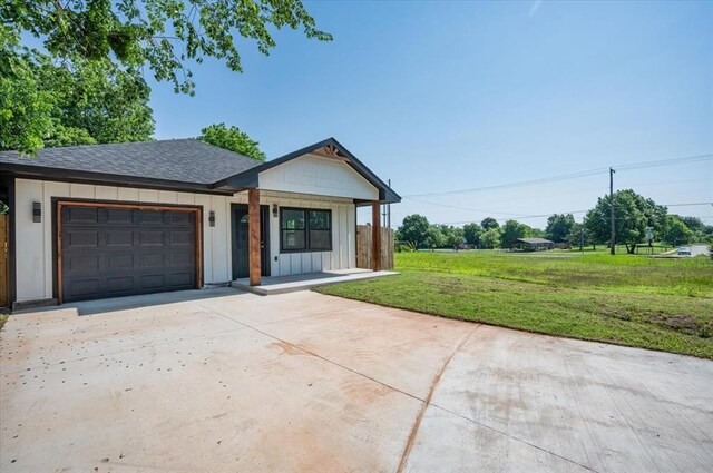 1435 NE 27th St, Oklahoma City, OK 73111 - view of front of home with an attached garage, board and batten siding, driveway, a front yard, and a shingled roof