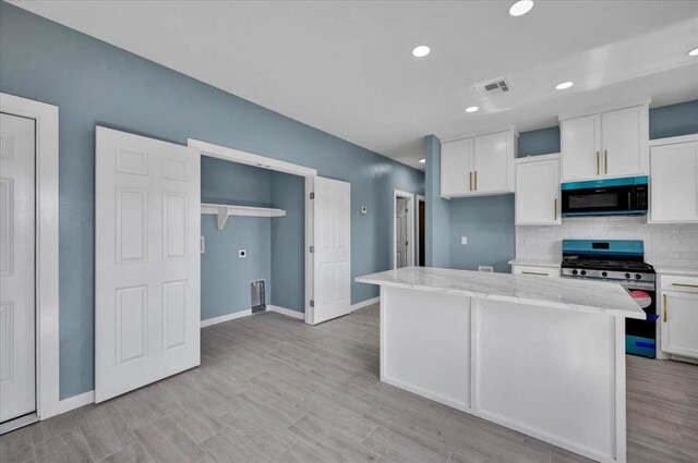 1435 NE 27th St, Oklahoma City, OK 73111 - kitchen with stainless steel gas range oven, white cabinetry, a center island, backsplash, and recessed lighting