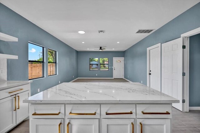 1435 NE 27th St, Oklahoma City, OK 73111 - kitchen featuring a ceiling fan, white cabinetry, light stone counters, open shelves, and a center island